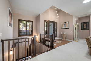 Hall featuring an upstairs landing, arched walkways, and carpet