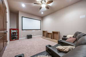 Carpeted cinema with a ceiling fan and recessed lighting