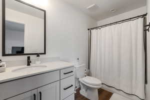 Bathroom featuring vanity, shower / bath combination with curtain, and dark wood-type flooring