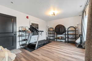 Workout room featuring wood finished floors and a textured ceiling