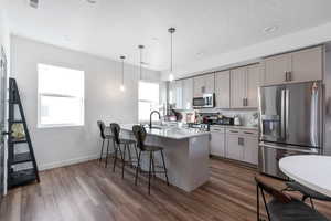Kitchen featuring stainless steel appliances, a peninsula, a kitchen bar, backsplash, and dark wood-style floors