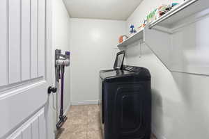 Laundry area with light tile patterned flooring and washing machine and clothes dryer