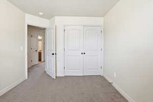 Unfurnished bedroom with light colored carpet and a closet