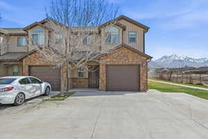 View of front of house featuring stone siding, board and batten siding, driveway, and an attached garage