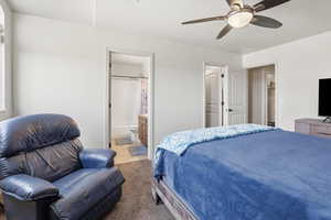 Bedroom with ceiling fan, connected bathroom, and light colored carpet