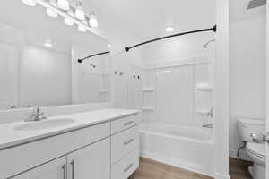 Bathroom with vanity, washtub / shower combination, and light wood-type flooring