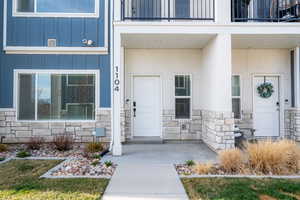 View of exterior entry featuring board and batten siding, stone siding, and a porch