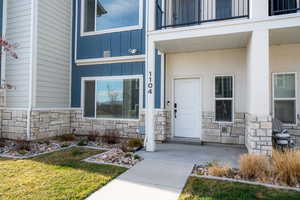 Doorway to property with stone siding, board and batten siding, and a yard