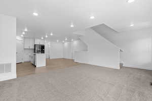 Unfurnished living room featuring light colored carpet and recessed lighting