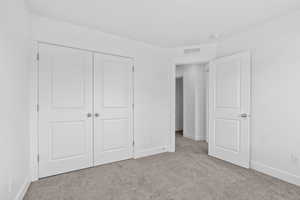 Unfurnished bedroom with light carpet and a closet