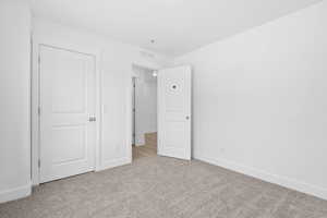 Unfurnished bedroom featuring light carpet and baseboards