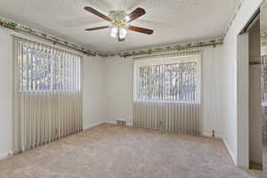 Carpeted empty room with a ceiling fan and a textured ceiling