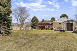 View of grassy yard with a mountain view, a storage unit, and a patio area