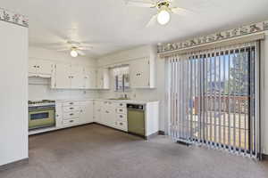 Kitchen with a ceiling fan, light countertops, a textured ceiling, white cabinetry, and dark carpet