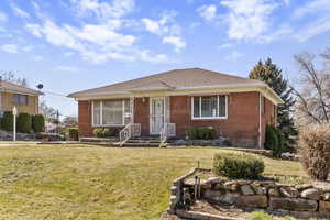 Bungalow-style house featuring a front lawn, brick siding, and roof with shingles