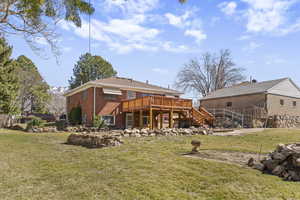 Back of property featuring a deck, a yard, and brick siding