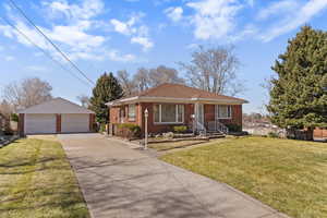 Bungalow-style home with an outdoor structure, a detached garage, and brick siding