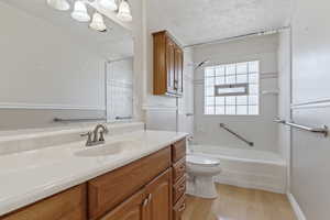 Full bath featuring vanity, light wood-style floors, a textured ceiling, and shower / washtub combination