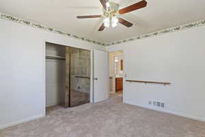 Unfurnished bedroom with a textured ceiling, carpet, a closet, and a ceiling fan