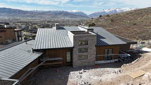 View of home's exterior featuring a standing seam roof, a mountain view, a chimney, and stone siding