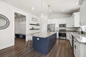Dual tone kitchen featuring two tone color scheme, stainless steel appliances, pendant lighting, a kitchen bar, and a kitchen island