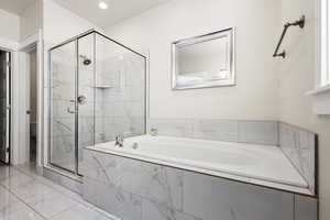 Full bathroom with a large format tile shower, a garden tub, and tile flooring