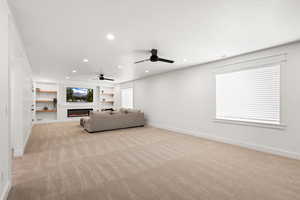 Living area featuring a custom-built entertainment center, high-end electric fireplace, high end carpet, recessed lighting,  dual ceiling ceiling fans