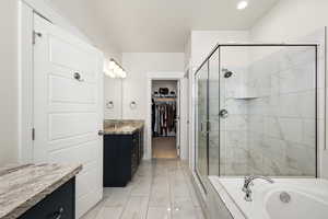 Bathroom with a spacious closet, a large tile shower, dual vanities, a garden tub, tile floors