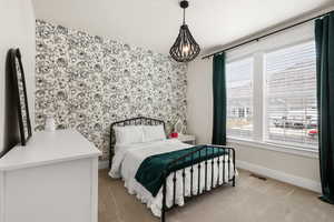 Bedroom featuring an accent wall, light carpet, and wallpapered walls