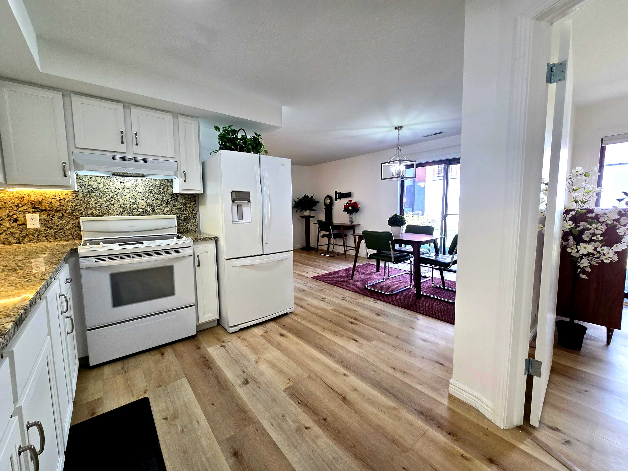 Kitchen with white appliances, white cabinets, and granite backsplash & countertops.