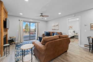 Living room featuring light wood finished floors, ceiling fan, recessed lighting, and a fireplace