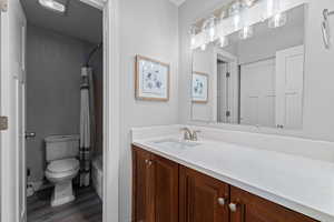 Bathroom featuring vanity, a textured wall, shower / tub combo with curtain, and dark wood-style floors