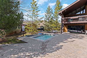 View of swimming pool featuring patio surround and an in-ground hot tub