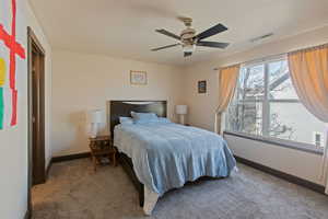 Carpeted bedroom featuring a ceiling fan and baseboards