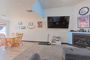 Living room with a glass covered fireplace, a textured ceiling, and wood finished floors