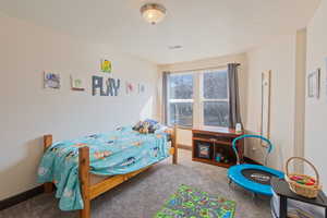 Bedroom with light colored carpet and a textured ceiling