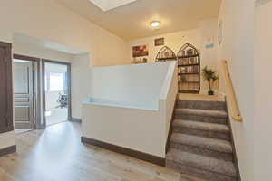Stairway featuring wood finished floors and a skylight