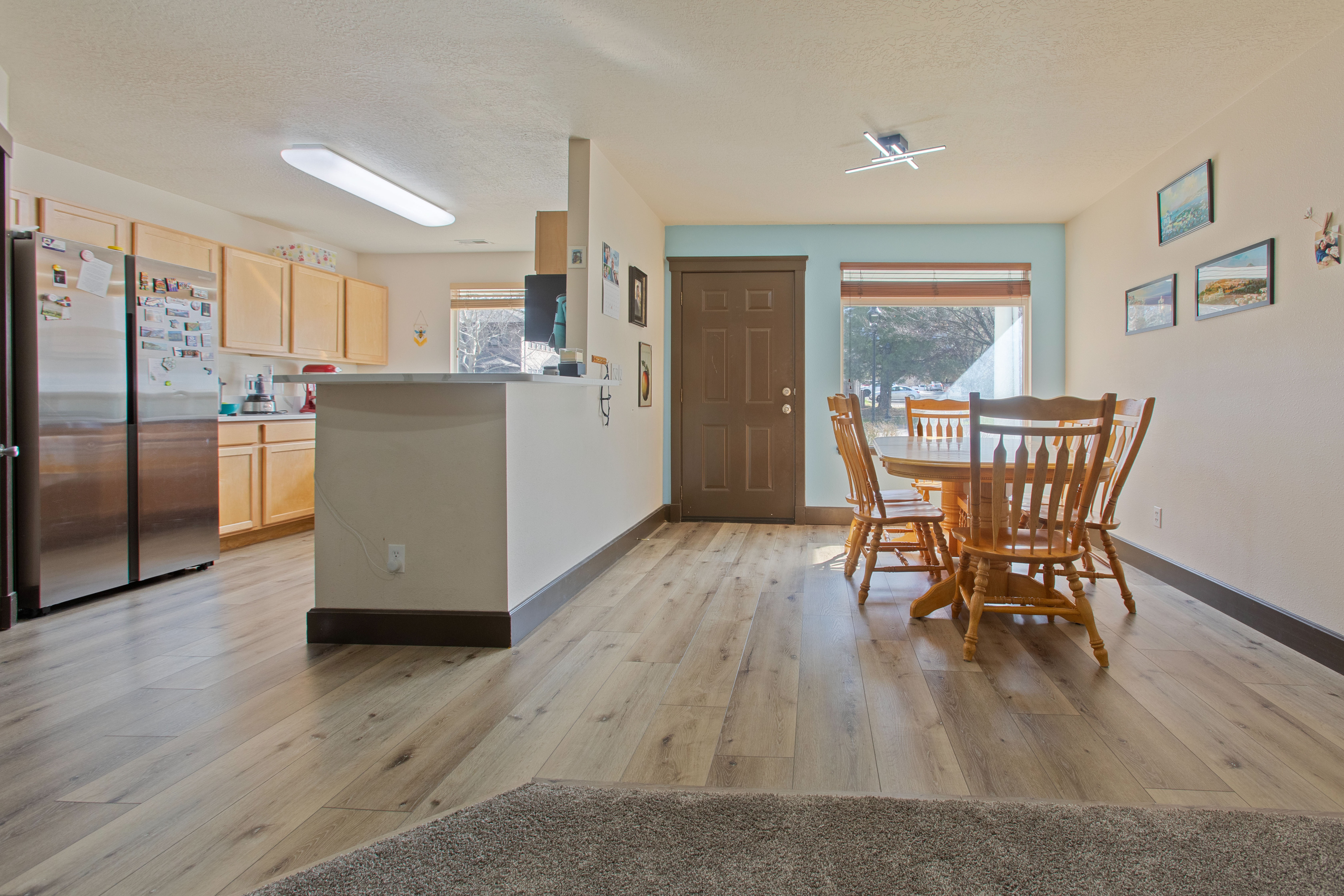 Kitchen with light wood finish cabinetry, freestanding refrigerator, light countertops, light wood-style floors, and a peninsula