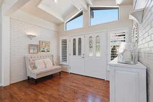 Entrance foyer featuring brick wall and dark wood finished floors