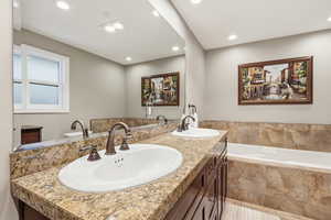 Bathroom featuring a garden tub, double vanity, and recessed lighting