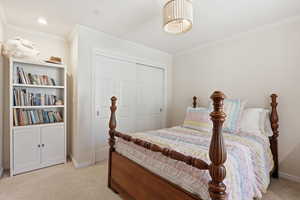 Bedroom with crown molding, a closet, and light colored carpet