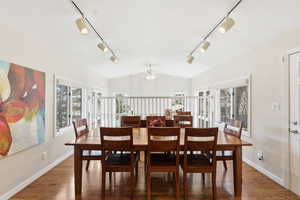 Dining space with ceiling fan, plenty of natural light, vaulted ceiling, wood finished floors, and rail lighting