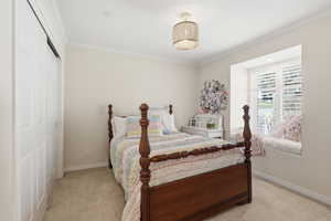Bedroom featuring a closet, crown molding, and light carpet