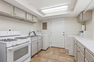 Kitchen with white range with gas cooktop, light countertops, washer / clothes dryer, and electric panel