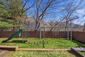 Fenced backyard featuring a playground