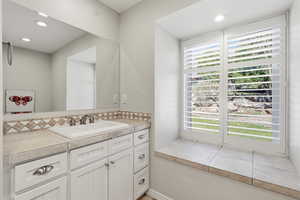 Bathroom with vanity, recessed lighting, and tasteful backsplash