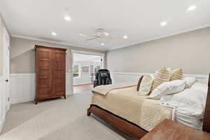 Bedroom with wainscoting, recessed lighting, a decorative wall, ornamental molding, and a ceiling fan