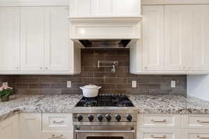 Kitchen with high end range, white cabinets, and light stone countertops