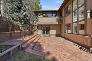 Rear view of house with a patio, french doors, brick siding, and a balcony