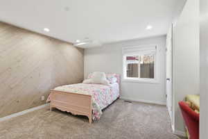 Carpeted bedroom with wood walls and recessed lighting